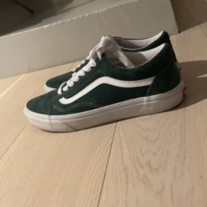 Gröna sneakers från Vans - Säljer ett par snygga gröna Vans sneakers i mocka. De har en klassisk vit sula och vit snörning som ger en stilren look. Perfekta för både vardag och fest! Skorna är i bra skick och redo för nya äventyr. Skorna är använda 2 gånger och säljer dom på grund av att dom inte passade mig. Priset kan sänkas vid snabb affär.