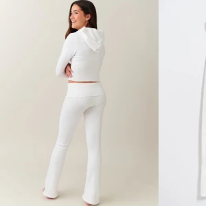 Vita stickade yoga byxor - Superfina vita stickade byxor som är både bekväma och stiliga. De har en låg midja och en loose passform som ger en avslappnad look. Perfekta för mysiga dagar hemma eller en chill dag ute. Matcha med en hoodie för den ultimata cozy stilen!