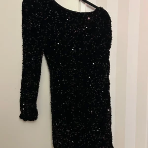 Svart paljettklänning - Snygg svart klänning täckt med glittriga paljetter, perfekt för en festkväll. Den har en tight passform och långa ärmar, vilket ger en elegant look. Klänningen är i mycket bra skick och redo att bäras till nästa stora event. Perfekt för nyår eller en glamorös utekväll!