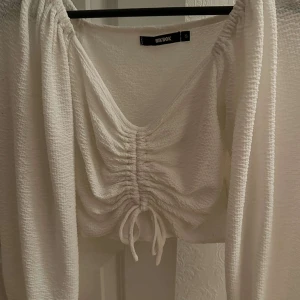 Vit ribbad topp från Bik Bok - Säljer en superfin vit topp från Bik Bok i storlek S. Den har en v-ringning och knytning framtill. 