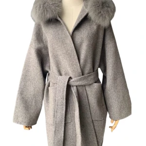 Grå kappa med pälskrage Dennis Maglic - Säljer en superfin grå kappa med fluffig pälskrage och huva. Den har ett bälte i midjan och stora fickor fram. Perfekt för kyliga höst- och vinterdagar. Kappan är i mycket bra skick och ger en elegant look. Passar både till vardags och fest!