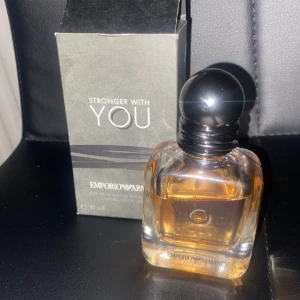 Stronger With You parfym från Emporio Armani - Säljer en elegant parfymflaska av Emporio Armani, 'Stronger With You'. Flaskan är stilren och genomskinlig med en svart rund kork. Doften är varm och kryddig, perfekt för kvällar och speciella tillfällen. Kommer i originalförpackning.