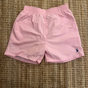 Rosa shorts från Polo Ralph Lauren - Säljer ett par snygga rosa shorts från Polo Ralph Lauren i storlek L, men passar mer som M. De har en elastisk midja och en liten broderad logga i blått på framsidan. Perfekta för sommardagar vid stranden eller poolen! 🏖️
