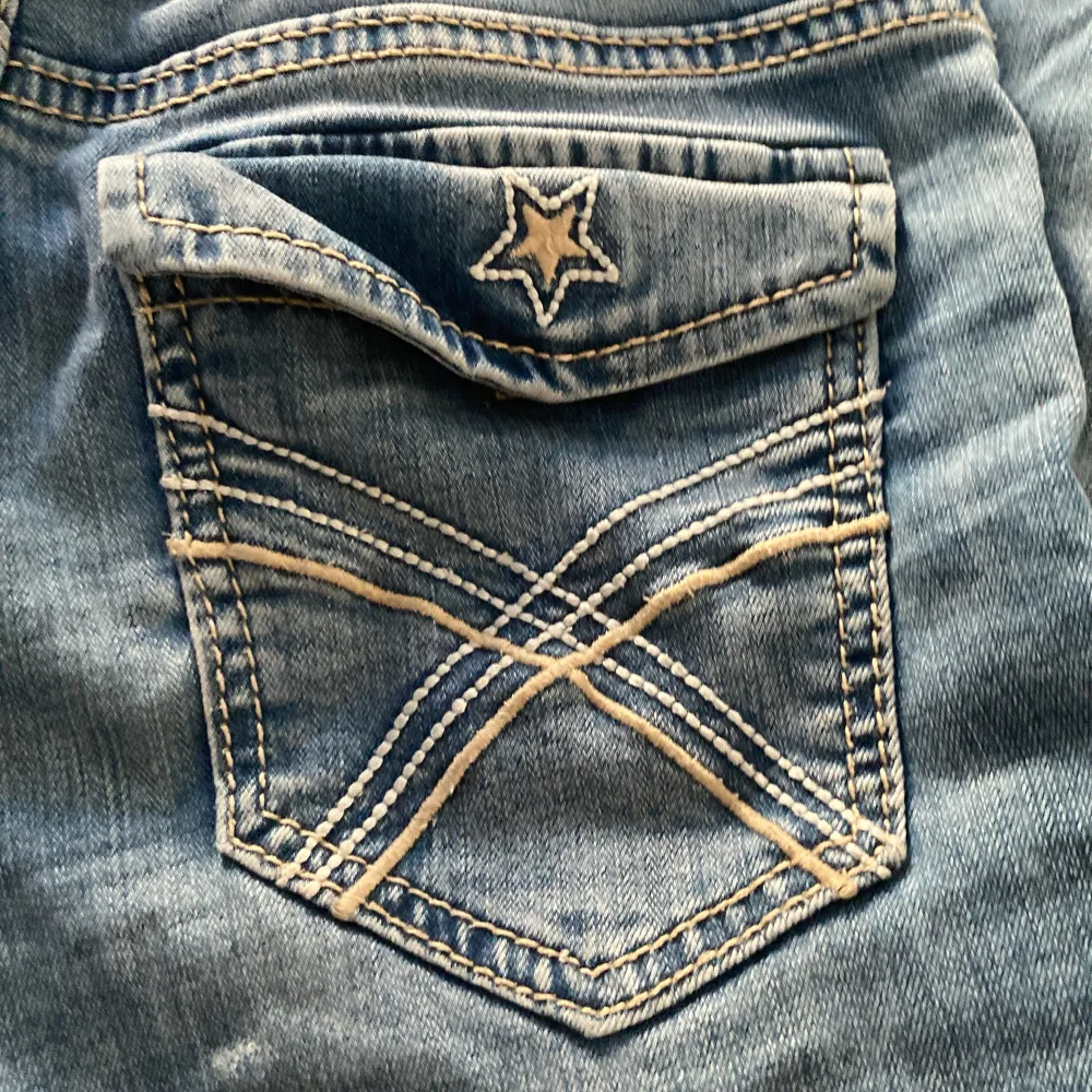 Säljer ett par snygga blå jeans från Lindex i ny skick. De har coola stjärndetaljer på bakfickorna och kontrastsömmar som ger en unik look. Perfekta för vardagsbruk eller en avslappnad utekväll. Passar bra till både sneakers och boots!Endast lite använda.. Jeans & Byxor.