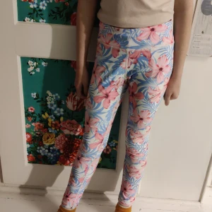 Blommiga leggings med snörning - Säljer ett par färgglada leggings med blommigt mönster i rosa och blått. De har en bekväm passform och snörning i midjan för justerbarhet. Perfekta för vår och sommar! 🌸
