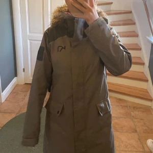 Grå vinterjacka KariTraa - Säljer en snygg och varm grå vinterjacka från Kari Traa. Jackan har en mysig pälsfodrad huva och långa ärmar. Perfekt för kalla vinterdagar! Den har praktiska fickor och en dragkedja framtill. Passar både till vardags och utomhusaktiviteter.