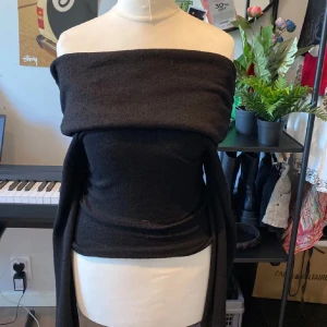 Svart offshoulder topp - Snygg svart offshoulder topp i ett mjukt material. Perfekt för en kväll ute eller en fest. Den har en tight passform som framhäver figuren och långa ärmar som ger en elegant look. Passar bra till både jeans och kjol.