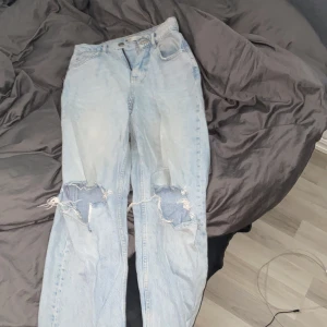 Ljusa jeans från Gina Tricot - Säljer ett par ljusa jeans från Gina Tricot i bra skick. De har en avslappnad passform med slitna detaljer på knäna för en trendig look. Perfekta för en casual outfit! 