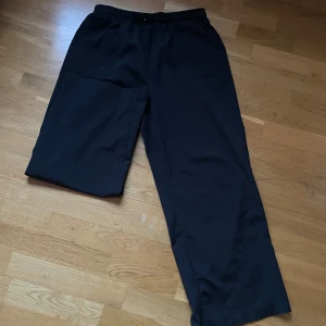 Svarta byxor med dragsko - Säljer ett par svarta byxor med elastisk midja och dragsko. Byxorna har en loose passform och är perfekta för en avslappnad stil. De har praktiska fickor framtill.