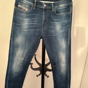 Blå jeans från Diesel - Snygga blå skinny jeans från Diesel med en klassisk femficksdesign och diskreta slitningar. Perfekta för en stilren look. Märkeslappen syns tydligt på baksidan.nypris 1200kr. 
