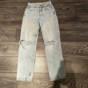 Ljusa jeans från Gina  - Säljer ett par ljusa jeans från gina tricot med slitna detaljer på knäna. De har en klassisk femficksdesign och en rak passform. Perfekta för en avslappnad stil. SKICLAS NYTVÄTTADE.