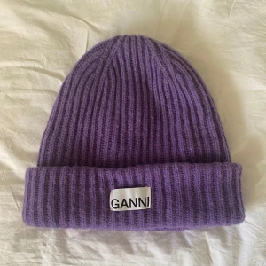 Lila mössa från Ganni i nyskick! - Säljer min fina Gannimössa som aldrig kommer till användning tyvärr. Supermjuk och skön, bara använd två gånger pga sitter lite för tight för min smak. I princip som ny, perfekt till vintern! Nypris 800:-
