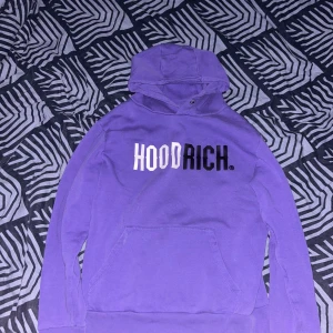 Lila hoodie från Hoodrich - Säljer en snygg lila hoodie från Hoodrich med texten 'HOODRICH' i vitt och svart på bröstet. Tröjan har en klassisk känguruficka och en bekväm huva. Perfekt för en avslappnad stil. Hör av dig vid fler frågor//Liam