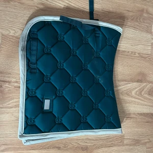 Equestrian Stockholm schabrak - Säljer mitt es schabrak i dressyrmodell och storlek full, färgen heter Amazonite och är just nu slutsåld. Pris kan diskuteras. Lite svart där på vita kanten men inget som syns när det används. Köpt helt nytt för ungefär 2 månader sen och är i nyskick förutom de svarta på kanten.