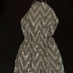 Glittrig klänning från Topshop - Snygg glittrig klänning från Topshop med ett zickzack-mönster i silver. Klänningen har en tight passform och är ärmlös med en halterneck-design. Perfekt för en festlig kväll! Nypris: 599 kr. Prislapp kvar