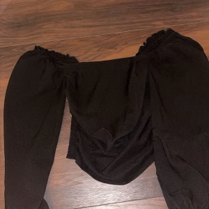 Svart offshoulder topp - Snygg svart offshoulder topp med puffiga ärmar och smockdetaljer. Använd fåtal gånger.