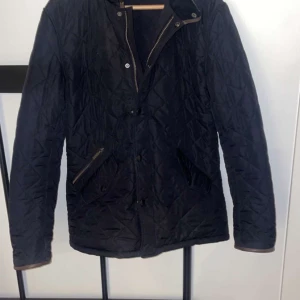 Marinblå barbour jacka - Snygg svart quiltad jacka med dragkedja och knappar. Perfekt för kyligare dagar med sin stilrena design och praktiska fickor. Skick 8/10 och passar S/M