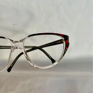 Transparenta glasögon med rödbrun mönster - Snygga glasögon med transparent front och rödbrun mönstrad båge. Den unika designen ger en modern och stilren look. Perfekt för dig som vill ha något annorlunda. Nya från 80-talet, kommer från en nedlagd optikbutik 