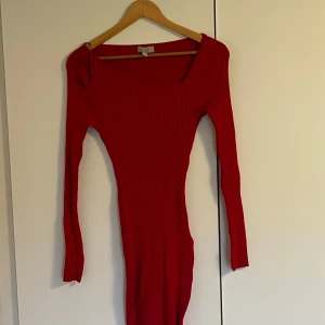 Röd ribbad klänning - Snygg röd ribbad klänning med lång ärm och en tight passform. Perfekt för en stilren look. Klänningen har en enkel design som framhäver figuren.