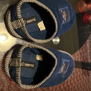 Blå tofflor från Pepperts - Mysiga blå tofflor från Pepperts med grå detaljer och texten 'COOL' på sulan. Perfekta för att hålla fötterna varma inomhus.