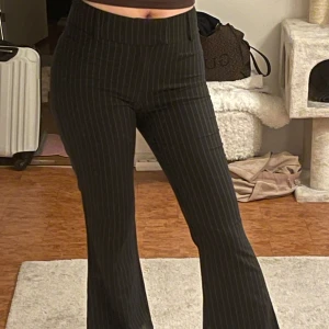 Randiga kostymbyxor  - Snygga svarta byxor med vita ränder från Gina Tricot. Byxorna har en medelhög midja och en bootcut-stil. Använt 1 gång. Väldigt snygg passform.