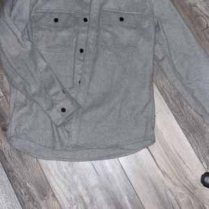 Grå overshirt/jacka - Tvär fet overshirt/jacka säljer då det inte va min storlek, passar sjukt bra till ett par svarta jeans och väldigt snygg med tshirt eller hoodie under. wow!