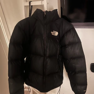 Svart dunjacka från The North Face - Svart pufferjacka från North face, i klassiska 1996 modellen, perfekt för kalla vinter dagar🤍Den är herr storlek XS, men passar unisex då jag som tjej använt den utan problem! Några få skavanker men fortfarande bra skick, kom privat för bild. Nypris 3900!