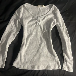 Grå ribbad tröja från Peter Alexander - Säljer en snygg grå ribbad tröja från Peter Alexander. Tröjan har långa ärmar och en knappdetalj framtill. Assnygg med ett par mörka jeans.