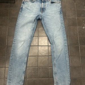 Ljusblå Lean Dean - Nudie Jeans - Säljer ett par ljusblå jeans från Nudie Jeans i passformen Lean Dean. Jeansen är i använt bruk och har som sagt några märken men är i ett bra skick ändå! 