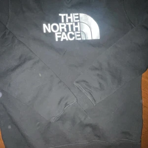 Svart tröja från The North Face - Säljer en svart tröja från The North Face med deras ikoniska logga i vitt på bröstet. Tröjan har långa ärmar och en klassisk rund halsringning. Perfekt för en avslappnad stil.