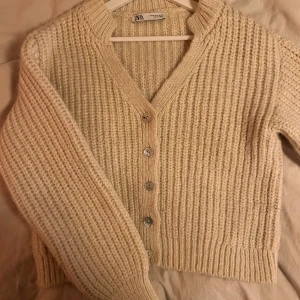 Beige stickad kofta från Zara - Säljer en mysig beige stickad kofta från Zara med knappar framtill. I stl M