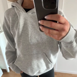 Grå hoodie - Säljer en bekväm och stilren grå hoodie med ficka och luva. Perfekt för en avslappnad look. Passar bra till både jeans och träningsbyxor. Den är lite nopprig