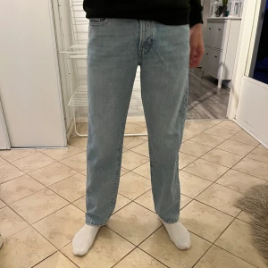 Ljusblå jeansbyxor - Säljer ett par ljusblå jeansbyxor med en straight passform. Byxorna har en klassisk design med fem fickor och knappgylf. Perfekta för en avslappnad stil. Använda bara en gång så fint skick! 