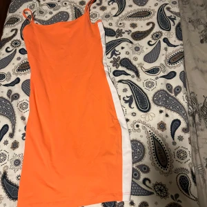 Neonorange klänning - En neonorange klänning med vita band på båda sidor. Skön att ha på sig på en sommarkväll eller så💞 