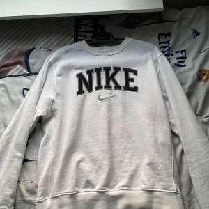 Vit långärmad tröja från Nike - Säljer en snygg och bekväm vit långärmad tröja från Nike. Den har en stor Nike-logga i svart på bröstet och är perfekt för både vardag och träning. Tröjan är i bra skick.