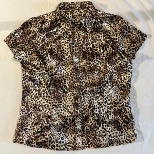 Skjorta i leopardmönster - Kortärmad skjorta i leopardmönster med diamant-knappar. Köpt second hand. Står storlek 44 men passar S/M lite baggy