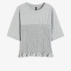 Topp med volang  - Säljer denna helt slutsålda och superfina grå topp från h&m som är ribbad och har en volang nedtill!! Den är använd 1-2 gånger och säljer den då jag har en likadan i vit💗💗