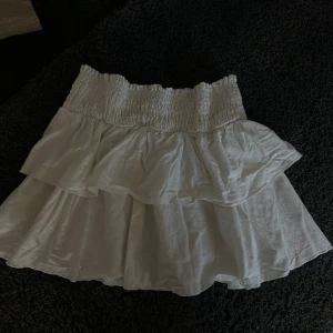 Vit volang kjol - Säljer denna vita volang kjol som aldrig kommer till användning. Inte genomskinlig och som ny. Har inte strykt den på bilden så lite dålig bild men den är väldigt fin och har resorband i midjan. Perfekt till höst! 