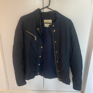 Marinblå jacka från Holly & Whyte - Säljer en snygg marinblå jacka från Holly & Whyte by Lindex. Den har en dragkedja och knappar i guld. Jackan är perfekt för höst och vår. 