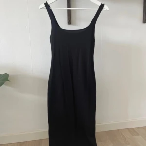 Svart klänning med slits - Svart tajt klänning med en liten slits där bak
