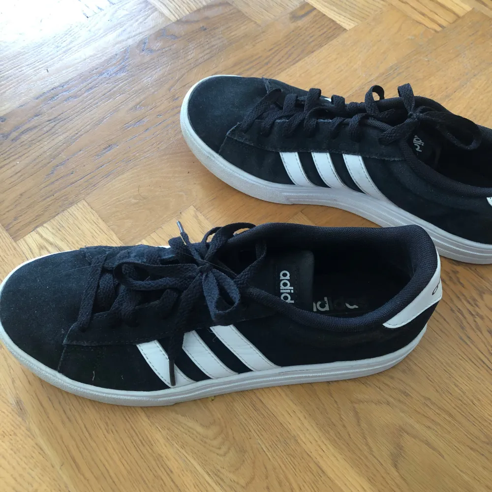 Säljer ett par snygga svarta Adidas sneakers i bra skick. De har den klassiska tre-randiga designen i vitt på sidan och är perfekta för vardagsbruk. Skorna har snörning och en bekväm passform. Perfekta för både vår och höst!. Skor.