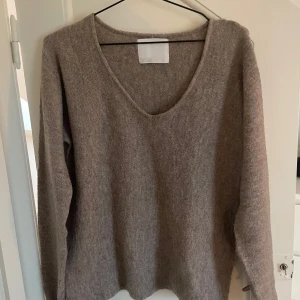 Beige brun stickad tröja - Mysig beige/brun stickad tröja från Gekås Ullared märket Samsa Collection i storlek S. Den har en v-ringad hals och är långärmad, perfekt för kyliga dagar. Materialet är mjukt och bekvämt, vilket gör den perfekt för vardag och mysiga hemmakvällar!🤍
