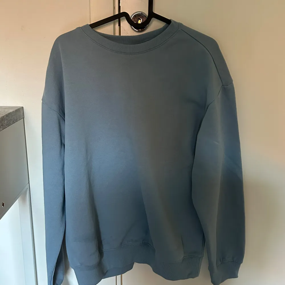 Säljer en stilren blå sweatshirt i mycket bra skick. Den har en klassisk rund hals och långa ärmar, perfekt för både höst och vår. Materialet känns mjukt och bekvämt, idealiskt för en avslappnad look. Passar bra till jeans eller joggers!. Tröjor & Koftor.