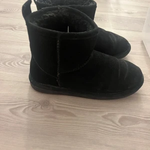 Svarta uggs med foder - Säljer ett par svarta uggs från Ella i mocka. Perfekta för kalla dagar med sin mysiga insida. 