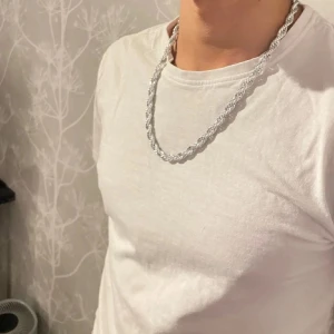 Silverfärgat halsband med glänsande design  - Säljer ett snyggt silverfärgat halsband med en cool tvinnad design. Perfekt för att ge din outfit lite extra stil. Halsbandet är i mycket bra skick och passar till både vardag och fest. Ett måste för alla som gillar att sticka ut!