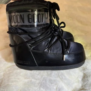 Svarta Moon Boots - Säljer ett par svarta låga Moon Boots i glansig design. Mycket bra skick.Nypris 2099kr❄️ Storlek 36- 38 (passar 35 -37) Perfekta för att hålla fötterna varma och torra i snön!