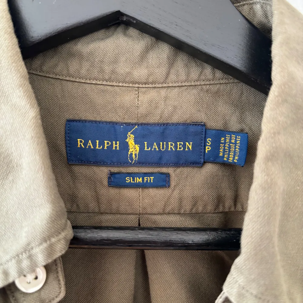 Säljer en snygg olivgrön skjorta från Ralph Lauren i slim fit. Skjortan har långa ärmar och klassiska knappar framtill. Den är broderad med Ralph Laurens ikoniska logga i orange på bröstet. Perfekt för både vardag och fest! 💛Väldigt bra skick 10/10. Skjortor.