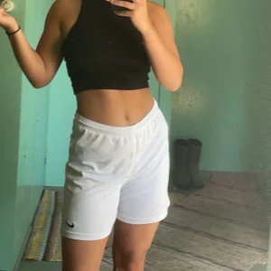 Vita träningsshorts från Nike - Säljer ett par vita träningsshorts från Nike i mycket bra skick. De är perfekta för träning och har en bekväm passform. Shortsen är midwaist och har en liten Nike-logga på benet. Perfekta för sommarens alla träningspass! 🏋️‍♀️
