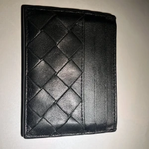 Bottega Veneta Black Card holder - Säljer en Bottega Veneta Cardholder. Perfekt för att hålla dina kort och kontanter organiserade. Den är i mycket bra skick och passar till alla tillfällen. En klassisk accessoar som aldrig går ur stil!