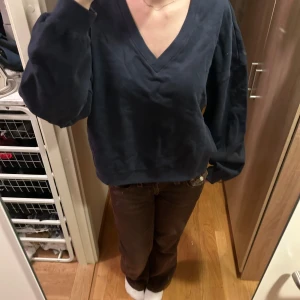 Mörkblå v-ringad tröja - Säljer en mörkblå v-ringad tröja i bra skick. Den har en loose passform och långa ärmar, perfekt för höst och vinter. Tröjan är enkel och stilren, vilket gör den lätt att matcha med olika outfits. Perfekt för både vardag och mysiga hemmakvällar.